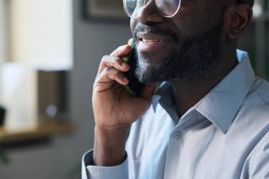 Gözlüklü, sakallı, telefonda konuşan neşeli, genç bir Afrikalı Amerikalı menajer.