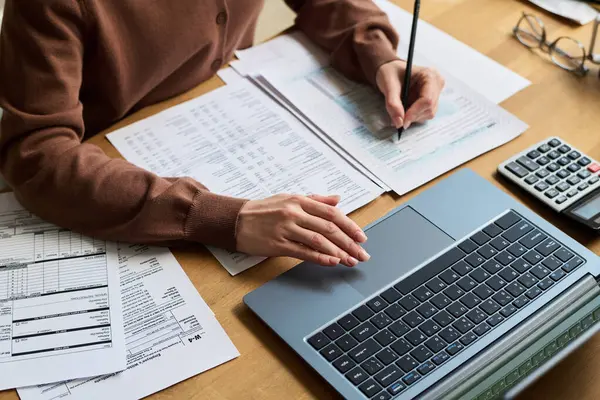 Masa başında otururken ve bütçeyi yönetirken, iç harcamaları ve kamu hizmetleri faturalarını hesaplayan genç bir kadının el kameralarına yüksek açı yakın çekim