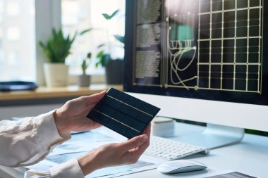 Tanımlanamayan tasarımcı bilgisayarın önünde oturmuş yenilikçi güneş paneli cihazının modelini inceliyor.