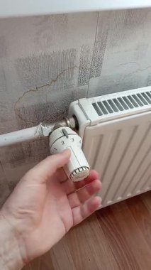 Bir adamın eli pille çalışan radyatörü çevirir..