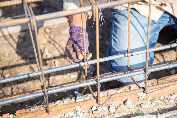 Worker are using wire and pliers to tie the rebar used for building foundations.