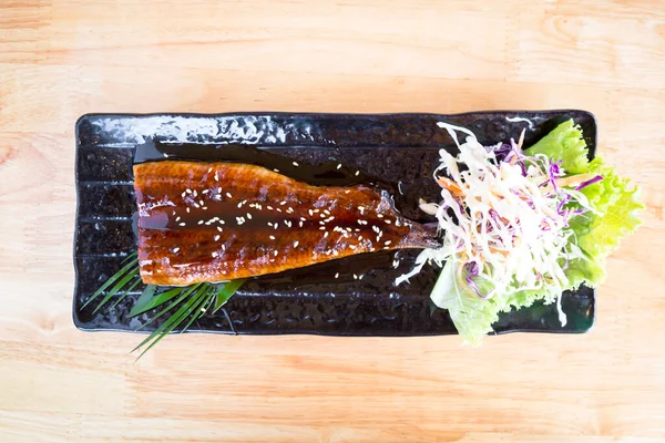 在精美的烤日本鳗鱼味道鲜美的烤盘上享用 精美地陈列在一张木制桌子上 — 图库照片