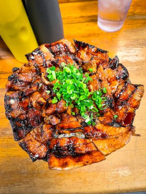 Bir tabak pastırma ve soğan ahşap bir masada oturur. Pastırma pişti, o ızgara, soğanlar doğrandı ve üzerine serpildi. Yemek lezzetli ve iştah açıcı görünüyor.