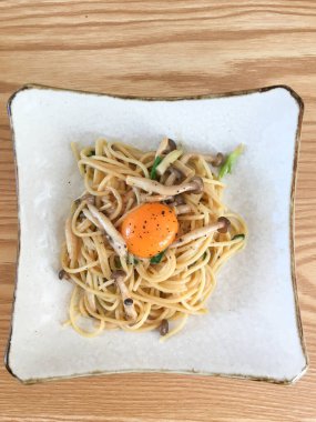 Mantarlı spagetti tabağı, taze otlar ve karabiberli çiğ yumurta sarısı..