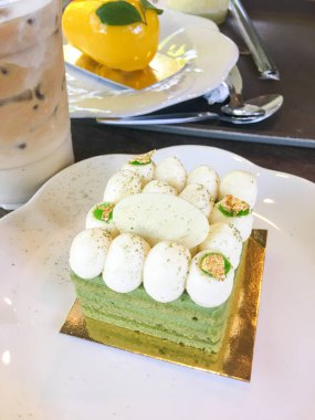 Krema küreleri, altın yaprak aksanları ve beyaz çikolatayla kaplı kibrit katmanlı bir tatlı..