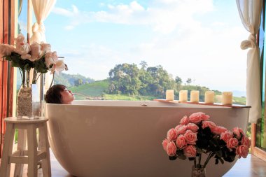 A serene moment soaking in a bath with stunning hillside views, surrounded by roses and candlelight. clipart