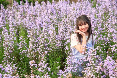 Pembe geleneksel kıyafetli bir kadın çiçek açan lavanta çiçeklerinin arasında zarif bir şekilde poz veriyor..