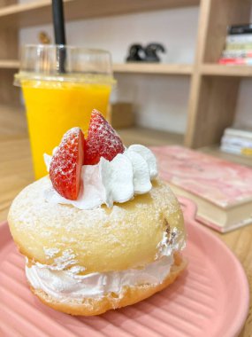 Üzerine taze çilek konmuş yumuşak kremalı çörek ve taze mango suyu.