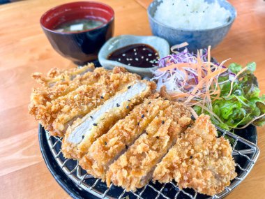 Pirinç, miso çorbası, salata ve sos ile servis edilen çıtır bir Japon domuz pirzolası.