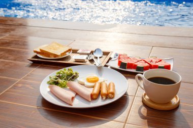 Serene havuz başında kahvaltıda kızarmış ekmek, taze karpuz ve doğal sabah ışığında çekilmiş kahve, dinlenme ve rahatlama temaları için mükemmel.