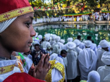 Gondar, Etiyopya, 19 Ocak 2023; Etiyopya 'nın Gondar kentinde Etiyopya Ortodoks kutlamaları olan Timkat' ı kutlayan Fasiladas hamamının etrafındaki kalabalığı izleyen sadık bir kadının yüzü.