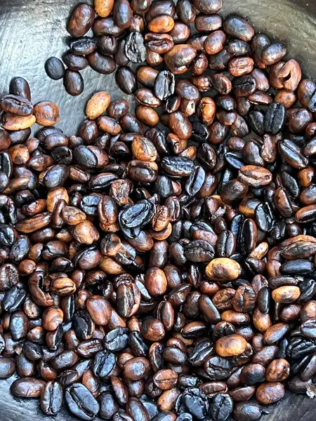 coffee beans being roasted by hand in the traditional way on a wood-fired stove.