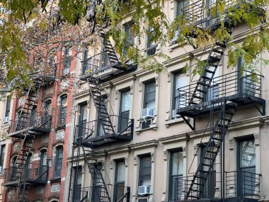 New York, Manhattan, Yukarı Doğu Yakası 'ndaki yangın merdivenli ve ağaçlı eski renkli binalar.