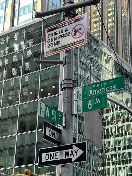 Traffic signs in a New York street, including a sign prohibiting the carrying of gun in the area. building in the background