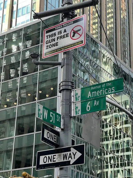 Traffic signs in a New York street, including a sign prohibiting the carrying of gun in the area. building in the background