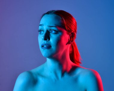 Head and shoulders close up portrait of pretty girl with expressive facial expressions, with  colourful neon gel lighting, isolated on studio background.