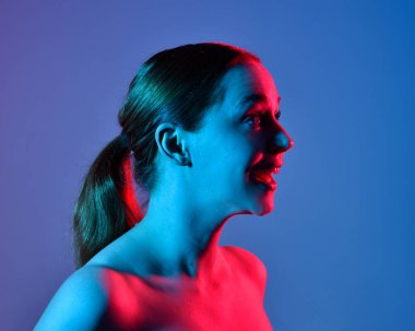 Head and shoulders close up portrait of pretty girl with expressive facial expressions, with  colourful neon gel lighting, isolated on studio background.
