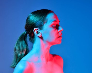 Head and shoulders close up portrait of pretty girl with expressive facial expressions, with  colourful neon gel lighting, isolated on studio background.