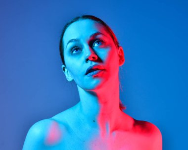 Head and shoulders close up portrait of pretty girl with expressive facial expressions, with  colourful neon gel lighting, isolated on studio background.