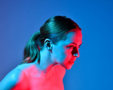 Head and shoulders close up portrait of pretty girl with expressive facial expressions, with  colourful neon gel lighting, isolated on studio background.