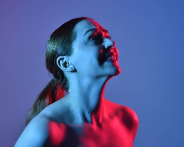 Head and shoulders close up portrait of pretty girl with expressive facial expressions, with  colourful neon gel lighting, isolated on studio background.