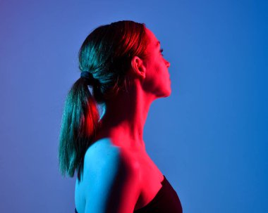 Head and shoulders close up portrait of pretty girl with expressive facial expressions, with  colourful neon gel lighting, isolated on studio background.