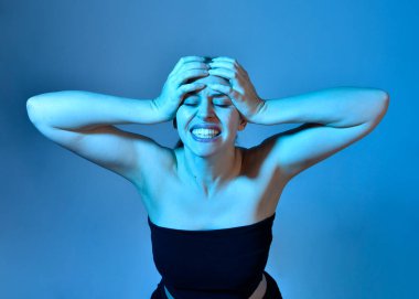 Head and shoulders close up portrait of pretty girl with expressive facial expressions, with  colourful neon gel lighting, isolated on studio background.