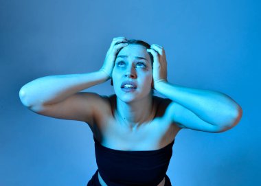 Head and shoulders close up portrait of pretty girl with expressive facial expressions, with  colourful neon gel lighting, isolated on studio background.
