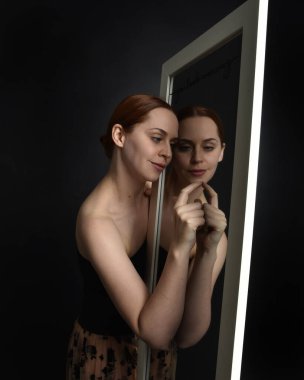 Close up portrait of beautiful girl looking into mirror, self reflection with colourful studio lighting. clipart