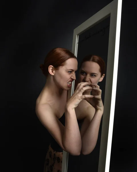 stock image Close up portrait of beautiful girl looking into mirror, self reflection with colourful studio lighting.