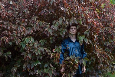 Close up portrait of young handsome man  interacting with  tree leaves