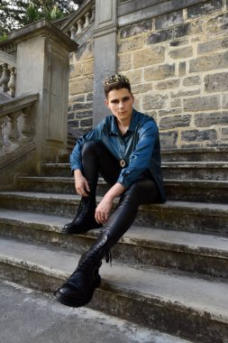 portrait of handsome brunette male model wearing fantasy medieval prince costume, romantic silk shirt. Wandering around historical castle location background with stone staircase.