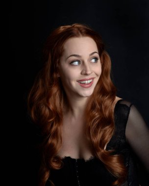 close up portrait of beautiful woman with long red hair wearing sheer corset top. variety of facial expressions,  Isolated on dark studio background with moody silhouette lighting.