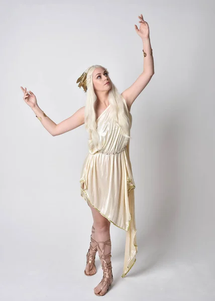 身穿奇幻女神托加服装 头戴魔法王冠的金发美女的全长肖像 站在那里 手伸着手跳舞 与白色画室背景隔离 — 图库照片