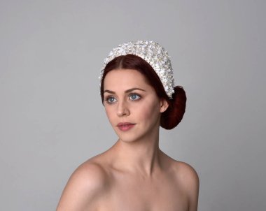 Stüdyonun arka planında zarif bir inci başlık takan güzel kızıl saçlı mankenin yakın plan portresi..