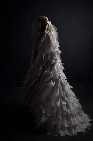 穿着超凡脱俗的白色羽毛斗篷服装和头饰的金发美女女模的幻想画像 在黑暗的工作室背景下被隔离 — 图库照片