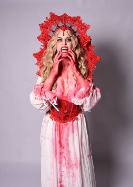 Korkunç vampir zombi kraliçenin portresi. Cadılar bayramı fantezi kostümü giymiş, kanlı kırmızı boya sıçramış. Stüdyonun arka planında el hareketleriyle kameraya uzanan izole bir şekilde..