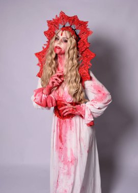 Korkunç vampir zombi kraliçenin portresi. Cadılar bayramı fantezi kostümü giymiş, kanlı kırmızı boya sıçramış. Stüdyonun arka planında el hareketleriyle kameraya uzanan izole bir şekilde..