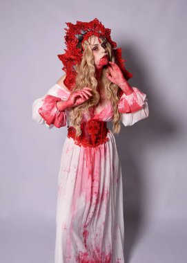 Korkunç vampir zombi kraliçenin portresi. Cadılar bayramı fantezi kostümü giymiş, kanlı kırmızı boya sıçramış. Stüdyonun arka planında el hareketleriyle kameraya uzanan izole bir şekilde..