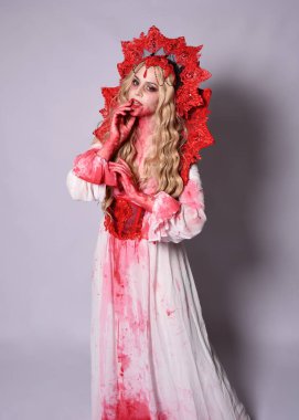 Korkunç vampir zombi kraliçenin portresi. Cadılar bayramı fantezi kostümü giymiş, kanlı kırmızı boya sıçramış. Stüdyonun arka planında el hareketleriyle kameraya uzanan izole bir şekilde..