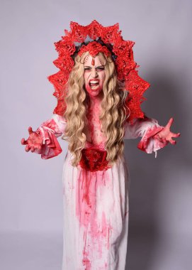 Korkunç vampir zombi kraliçenin portresi. Cadılar bayramı fantezi kostümü giymiş, kanlı kırmızı boya sıçramış. Stüdyonun arka planında el hareketleriyle kameraya uzanan izole bir şekilde..
