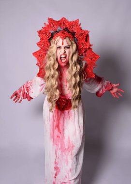 Korkunç vampir zombi kraliçenin portresi. Cadılar bayramı fantezi kostümü giymiş, kanlı kırmızı boya sıçramış. Stüdyonun arka planında el hareketleriyle kameraya uzanan izole bir şekilde..