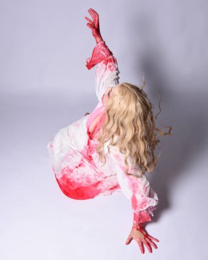  Korkunç vampir zombi gelinin portresi. Cadılar bayramı fantezi kostümü giymiş. Üzerinde kanlı kırmızı boya lekeleri var. Stüdyo arka planında izole edilmiş 