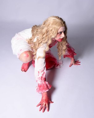  Korkunç vampir zombi gelinin portresi. Cadılar bayramı fantezi kostümü giymiş. Üzerinde kanlı kırmızı boya lekeleri var. Stüdyo arka planında izole edilmiş 