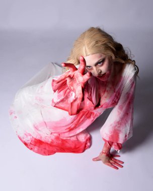  Korkunç vampir zombi gelinin portresi. Cadılar bayramı fantezi kostümü giymiş. Üzerinde kanlı kırmızı boya lekeleri var. Stüdyo arka planında izole edilmiş 