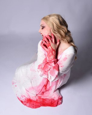  Korkunç vampir zombi gelinin portresi. Cadılar bayramı fantezi kostümü giymiş. Üzerinde kanlı kırmızı boya lekeleri var. Stüdyo arka planında izole edilmiş 