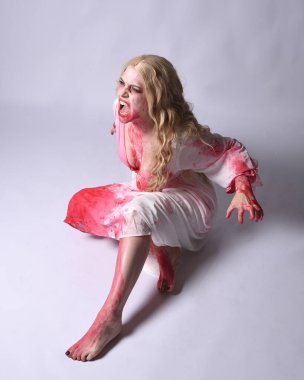  Korkunç vampir zombi gelinin portresi. Cadılar bayramı fantezi kostümü giymiş. Üzerinde kanlı kırmızı boya lekeleri var. Stüdyo arka planında izole edilmiş 