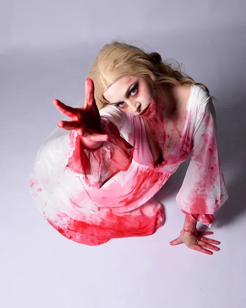  Korkunç vampir zombi gelinin portresi. Cadılar bayramı fantezi kostümü giymiş. Üzerinde kanlı kırmızı boya lekeleri var. Stüdyo arka planında izole edilmiş 