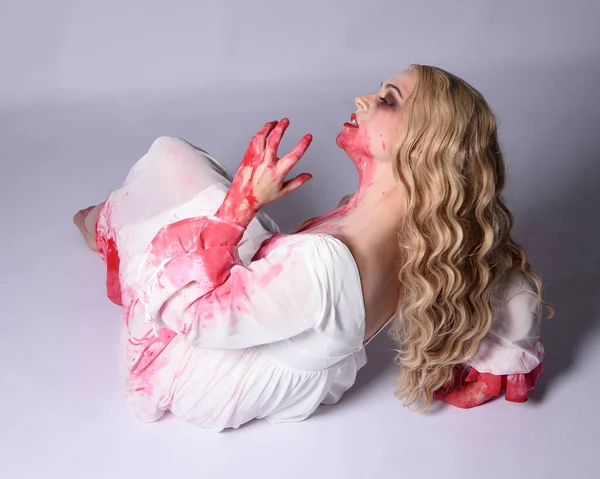  Korkunç vampir zombi gelinin portresi. Cadılar bayramı fantezi kostümü giymiş. Üzerinde kanlı kırmızı boya lekeleri var. Stüdyo arka planında izole edilmiş 