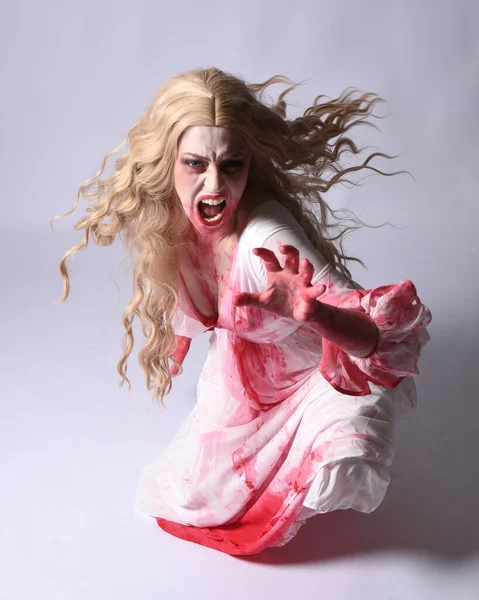  Korkunç vampir zombi gelinin portresi. Cadılar bayramı fantezi kostümü giymiş. Üzerinde kanlı kırmızı boya lekeleri var. Stüdyo arka planında izole edilmiş 
